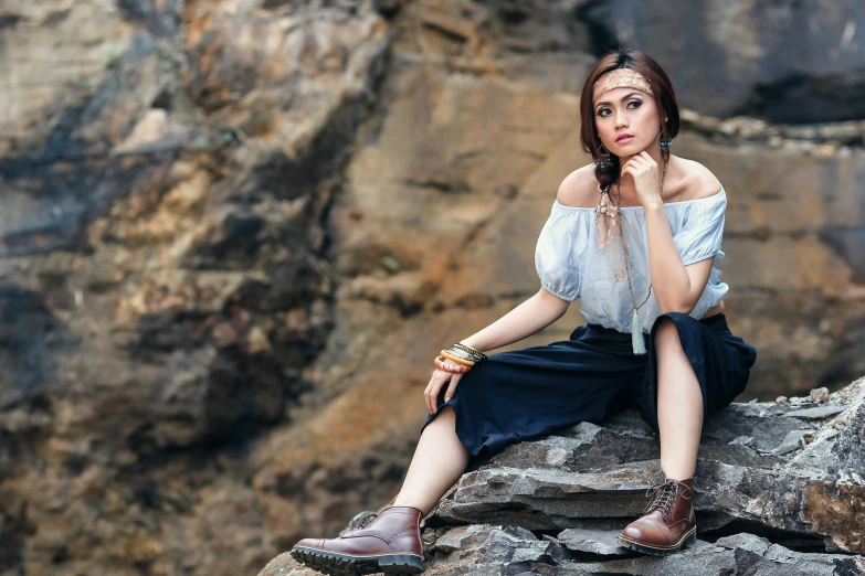 a woman sitting on top of a rock next to a large cliff