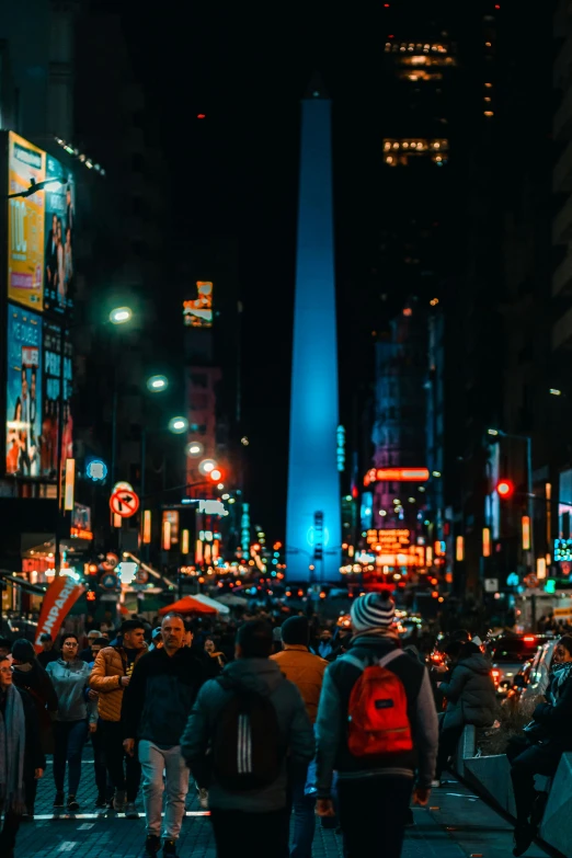 a group of people are walking down a city street at night