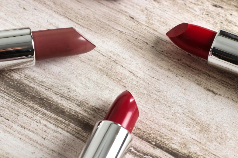 two red lipsticks laying on a wooden table