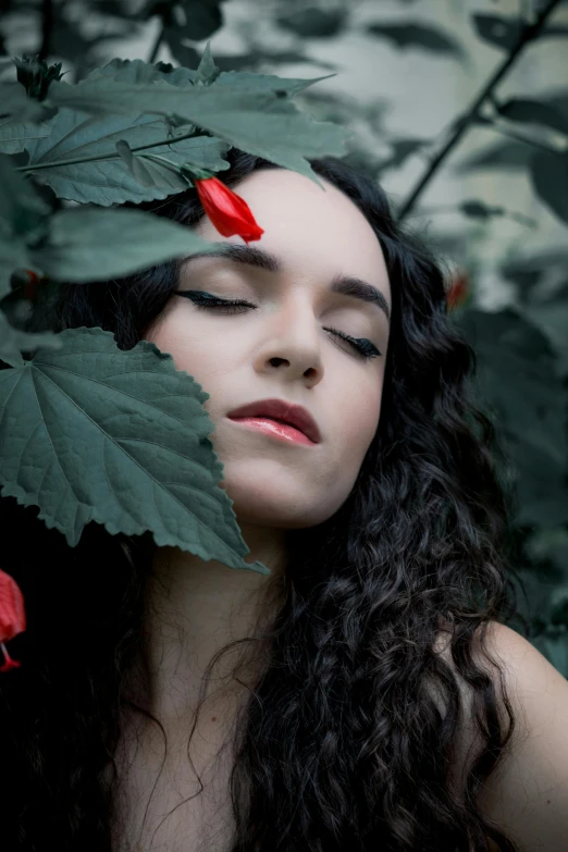 a woman that is standing behind a flower