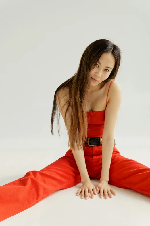 a woman in red sits on a white surface