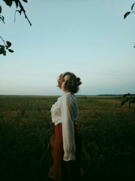 a woman in the grass and flowers at sunset