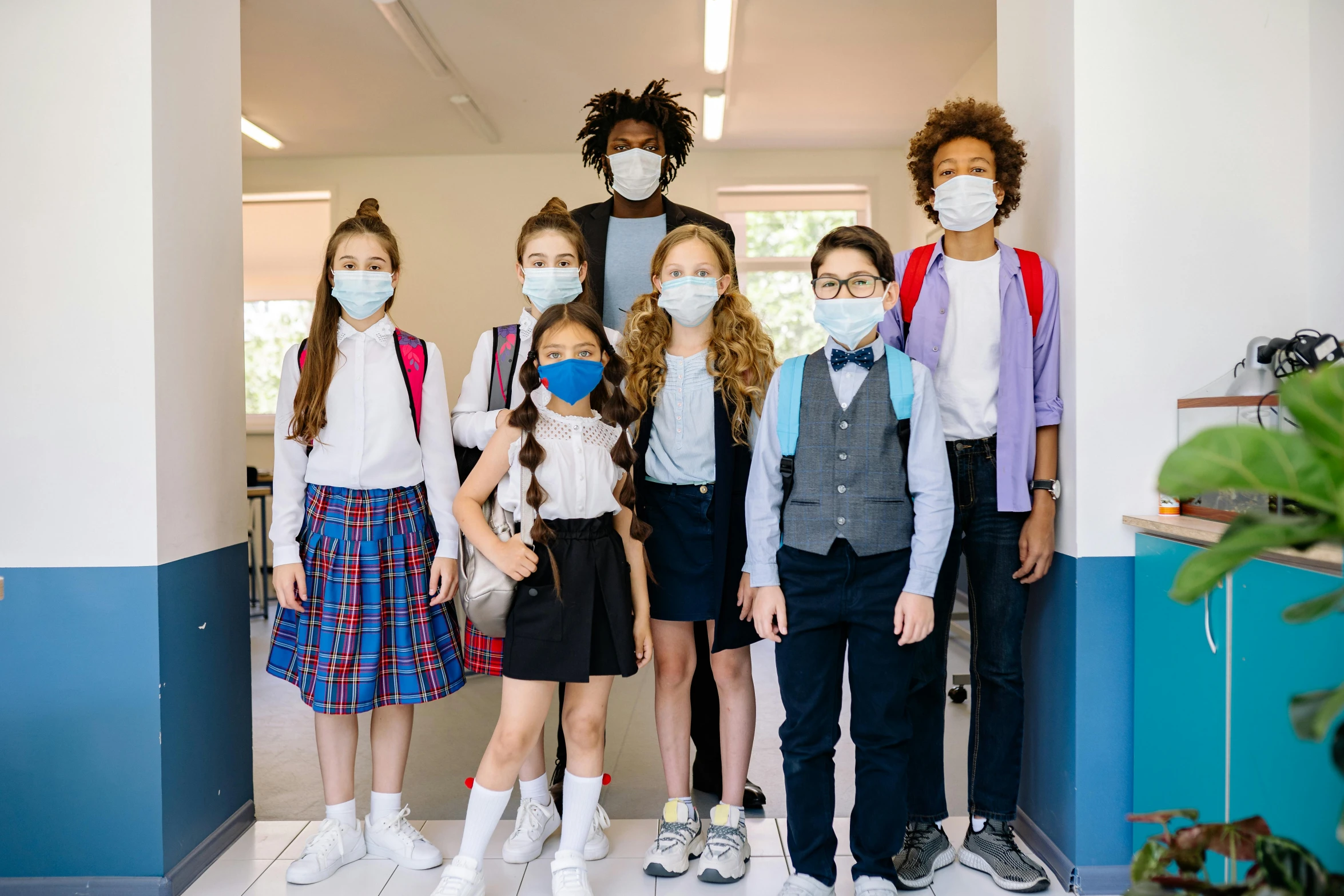 group of young children with masks posing for po in hallway