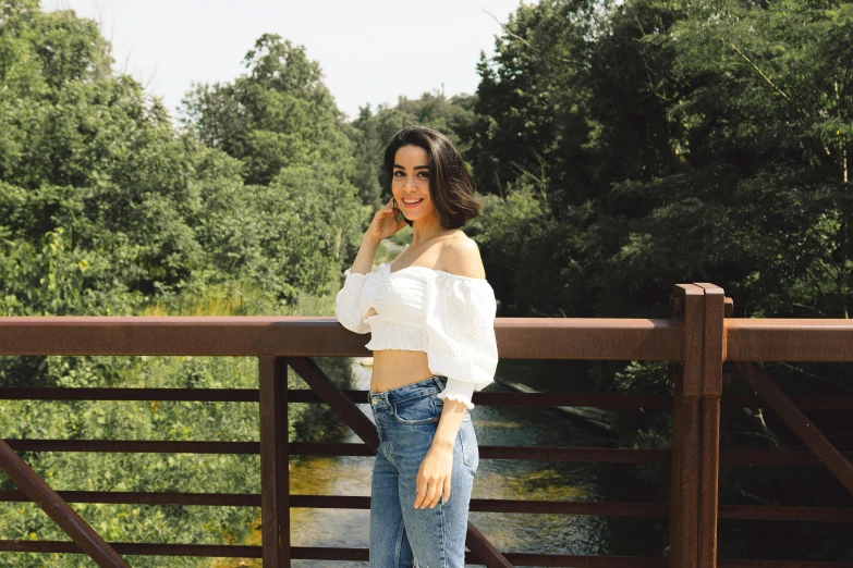 a woman poses for a picture on a wooden bridge