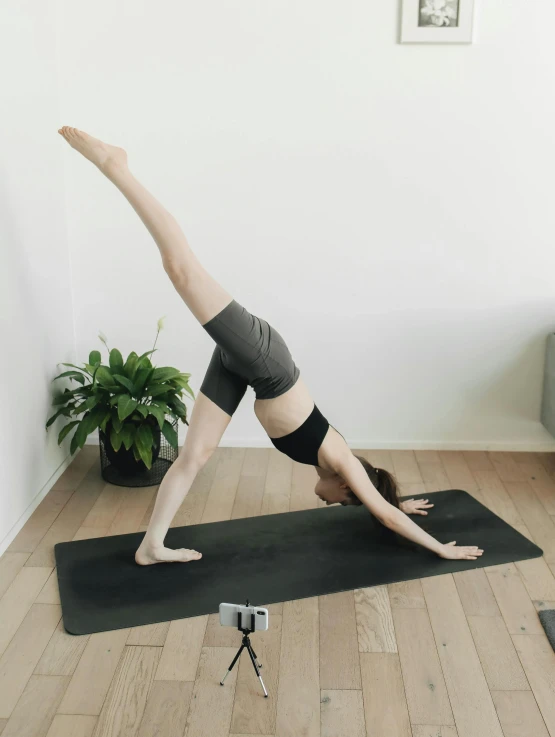 woman in a downward handstand poses with her leg in the air