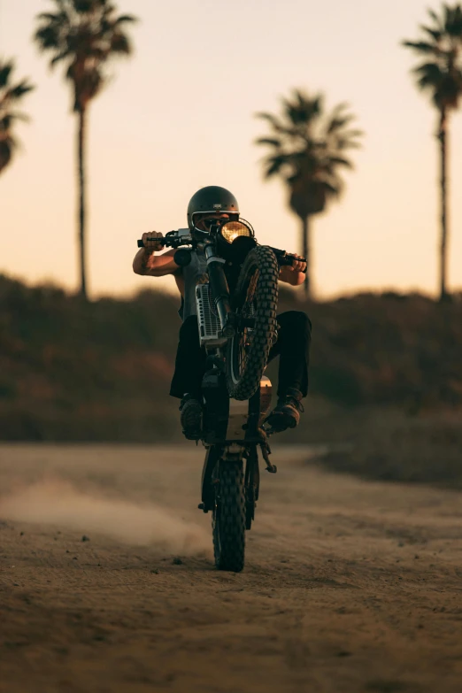 man on motor bike wearing black vest doing a wheelie