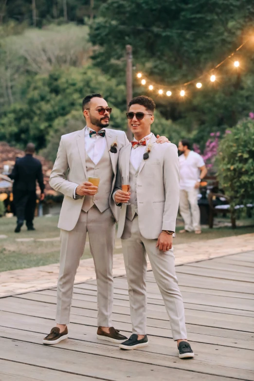 two men in matching suits standing together in front of the camera