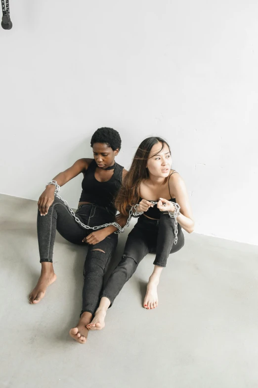 two young women sitting in a room and being roped together by a man