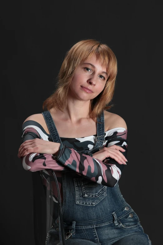 a woman in overalls with her arms crossed posing