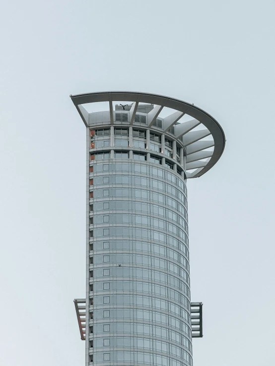 a tall circular glass building against a white sky