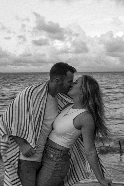 a man and woman kissing on the beach