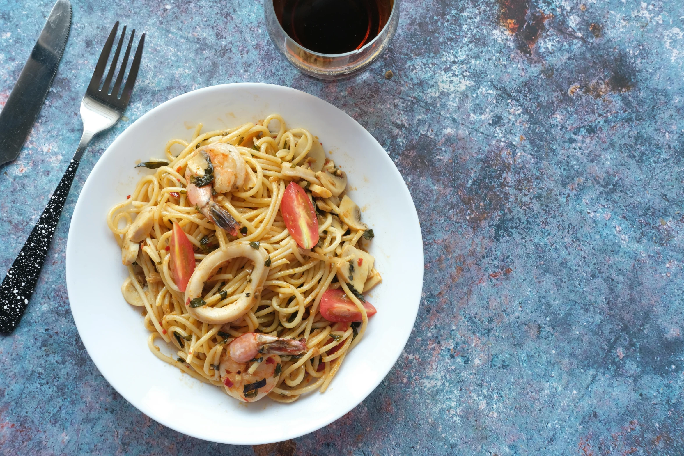 a bowl full of noodles, a fork and knife with liquid