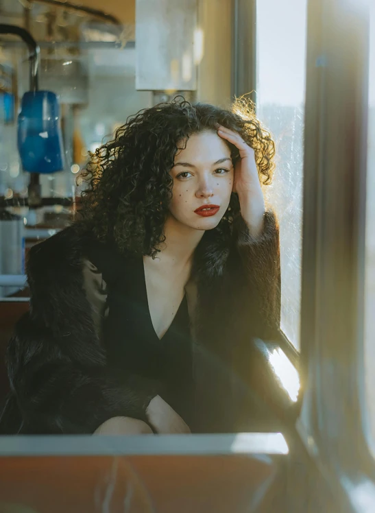 a woman is sitting by a window looking down