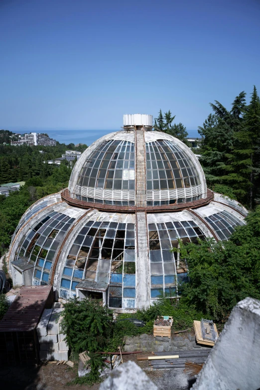 an ornate dome structure with glass and wood overhanging from the ground