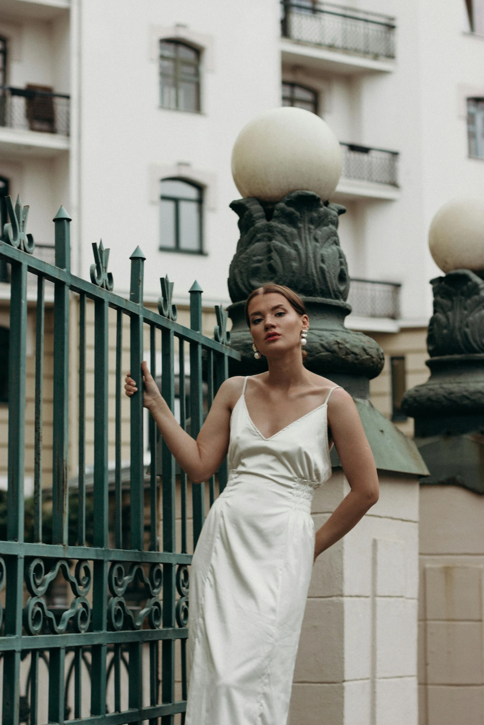 woman in white dress standing by iron fence