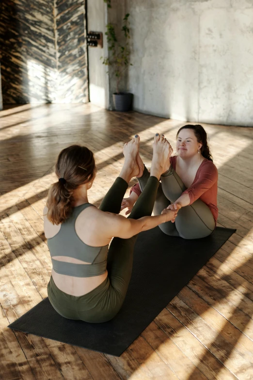 a woman doing yoga with another woman who is sitting down