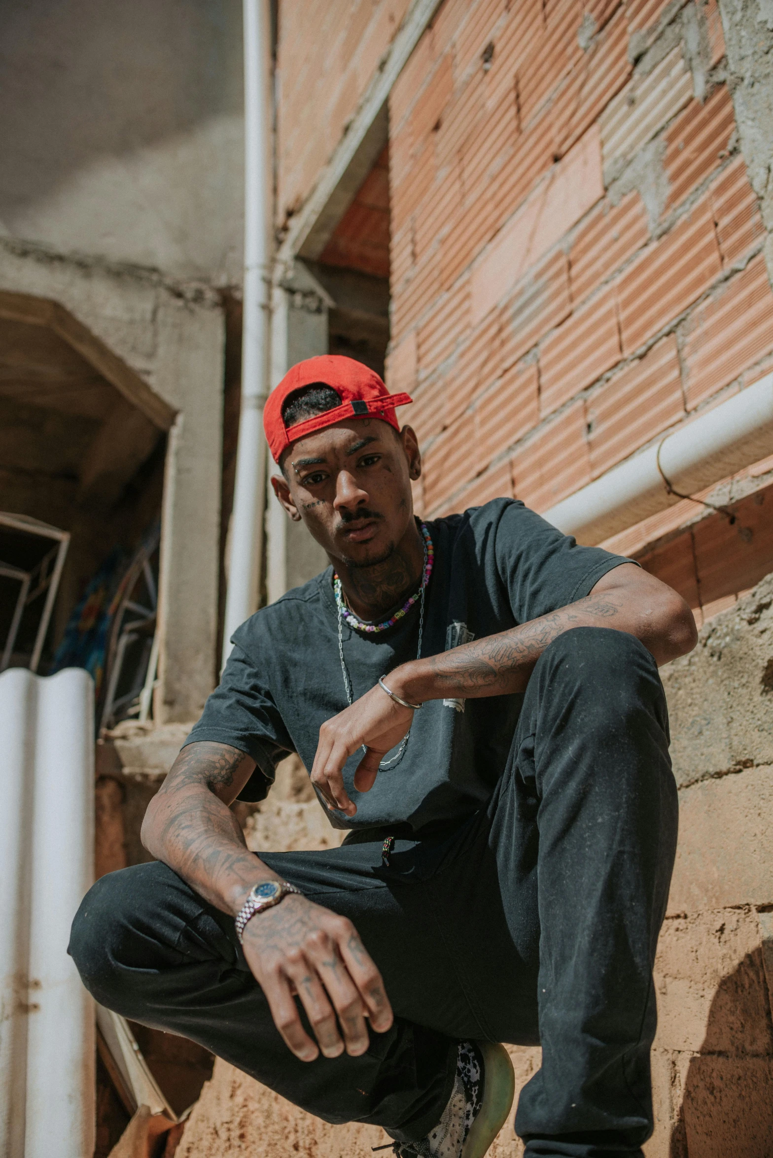 a man sits on a skateboard wearing a red cap and blue jeans