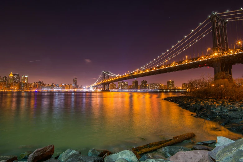 a view of the bay bridge, with a lit city in the background