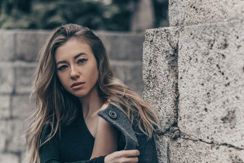 a woman leaning against a wall near the street