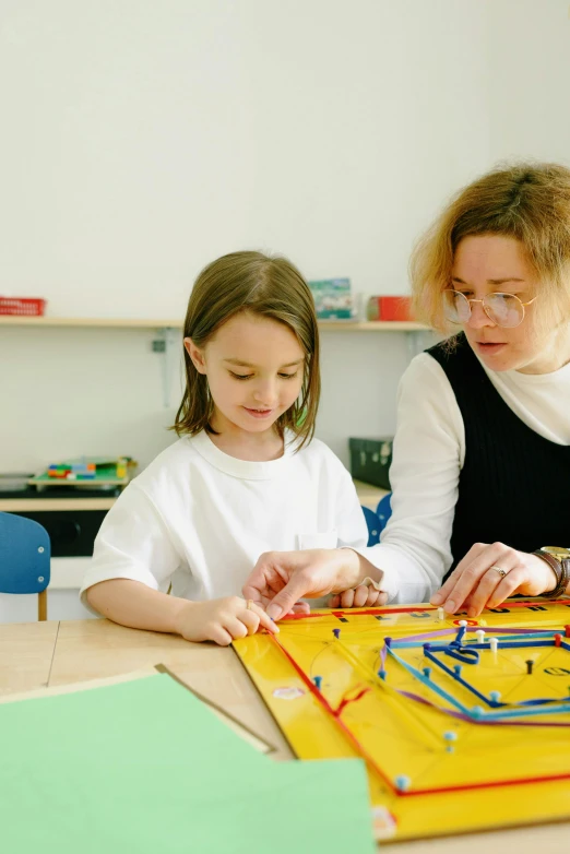 two girls looking at a piece of construction in the classroom