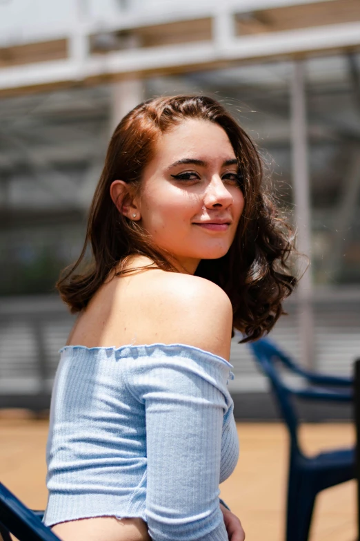 a girl is sitting in a chair while smiling at the camera