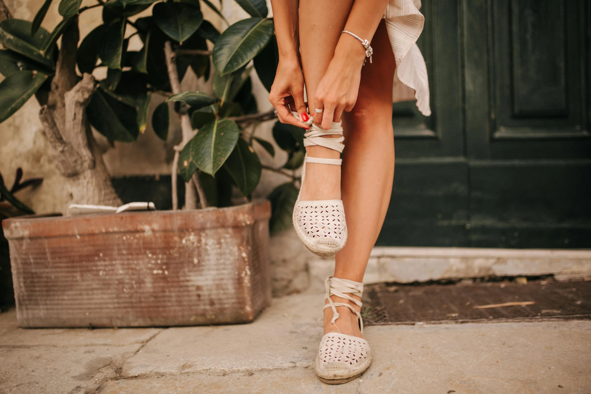 woman in white shoes is barefoot and is holding onto another pair