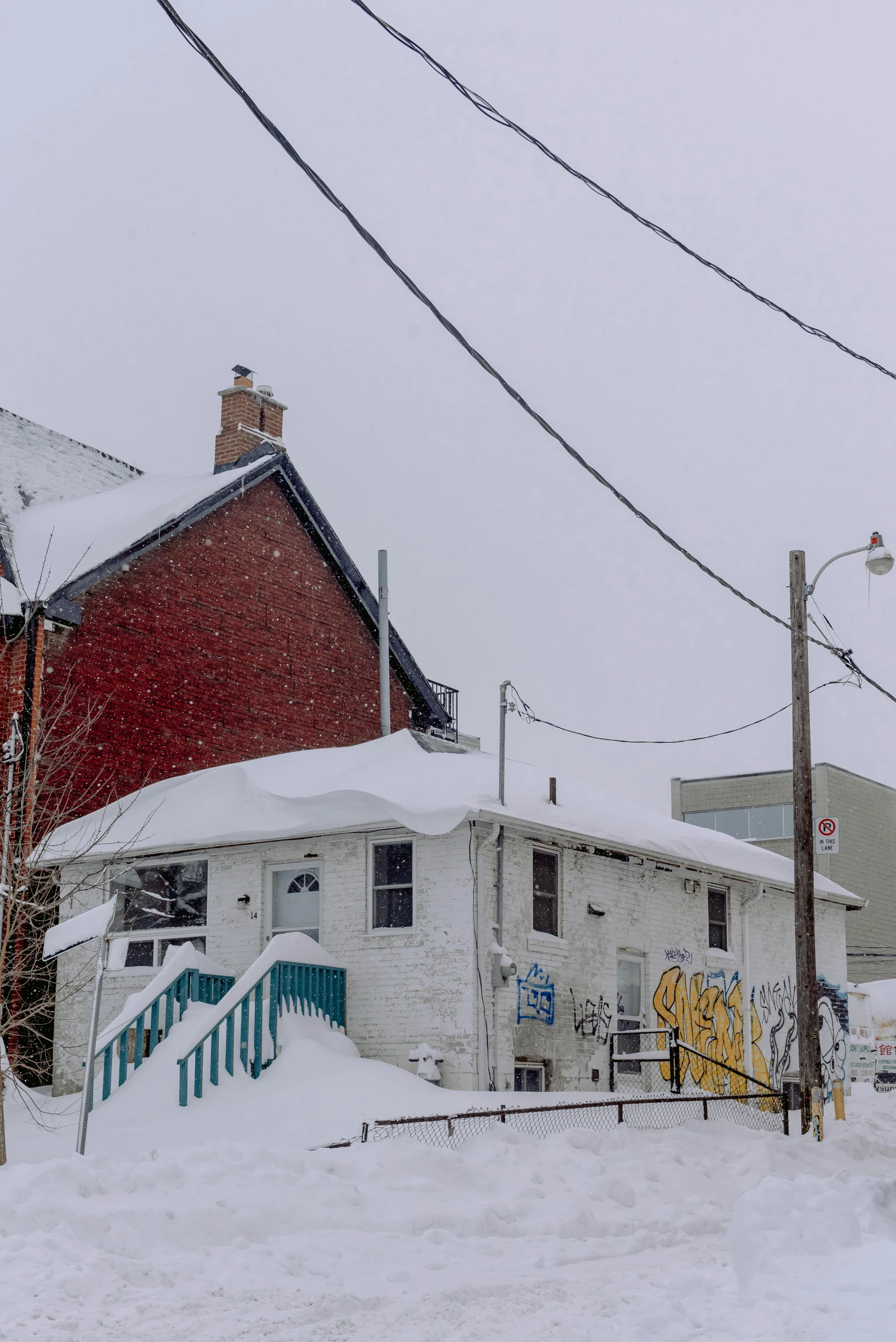 two houses covered in snow, one with a red door and one without a door, one without a door