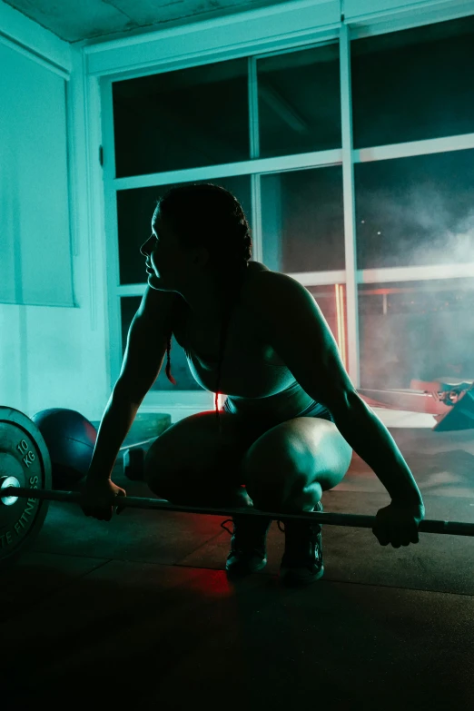 a women kneeling down while holding onto a barbell