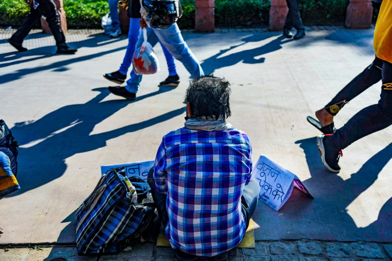 a man sits alone on the ground with his suitcase