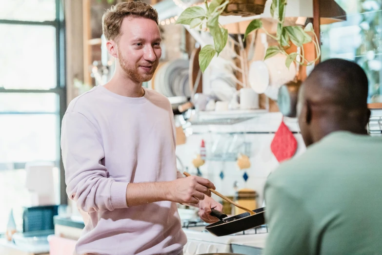 two men talking while one is cooking