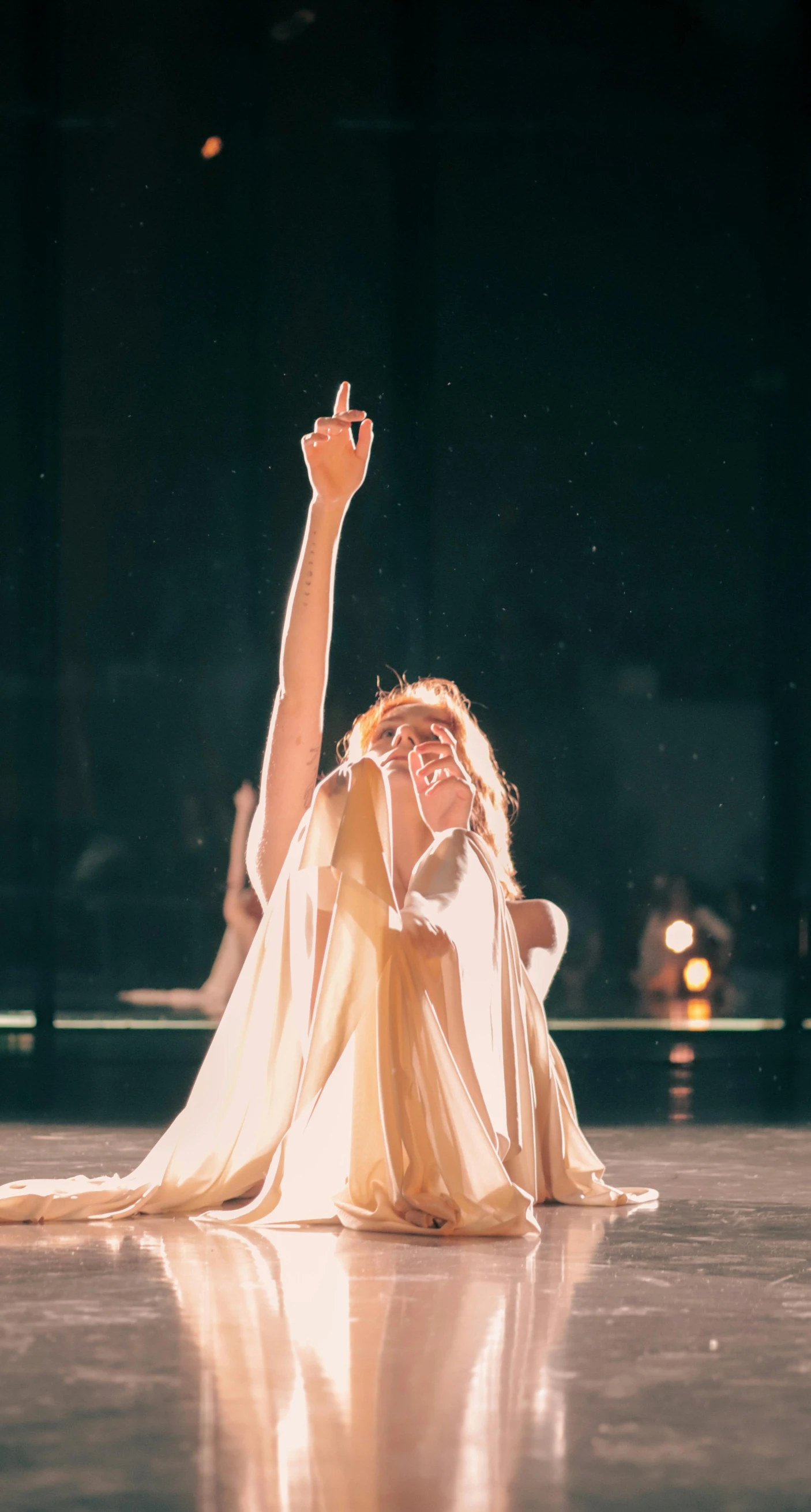 woman sitting on the ground with one hand up in the air