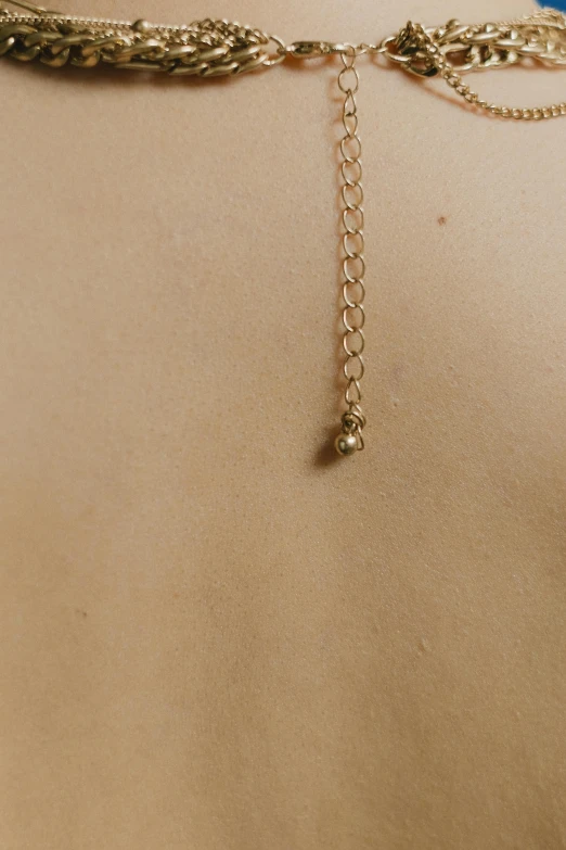 a close up of a woman's body and some gold chain