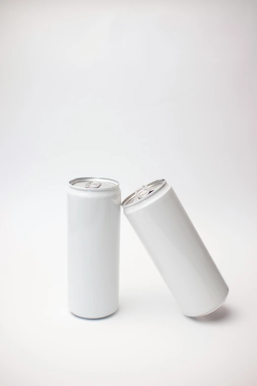 two small white cylindrical cups on a white surface