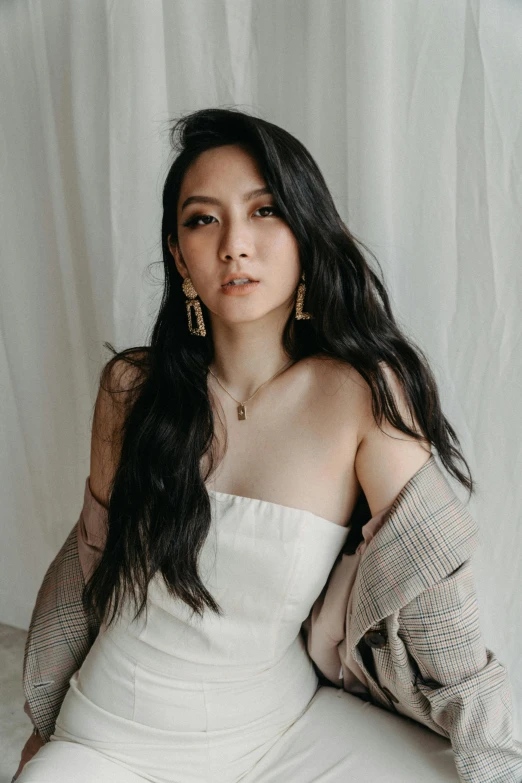 a young woman wearing large gold earrings and a white dress