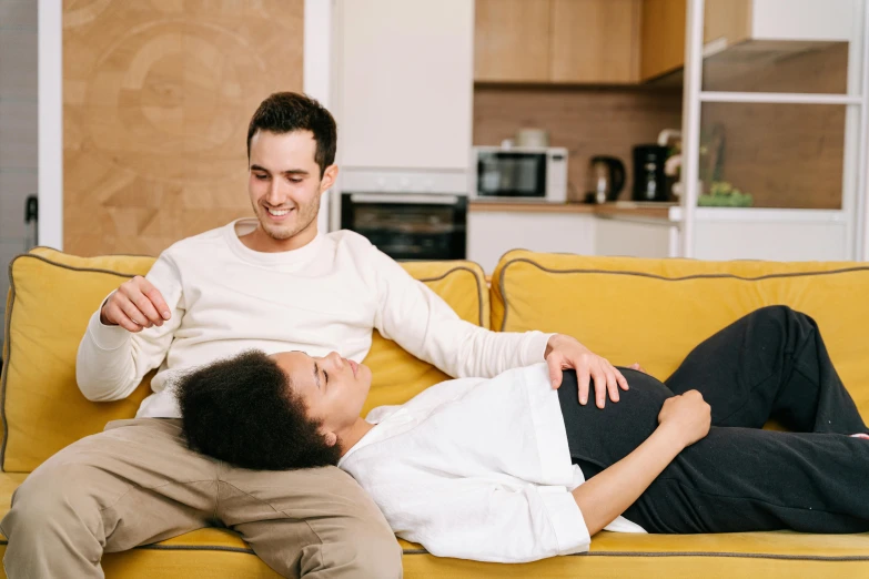 a man and a woman laying on a couch with their arms around each other