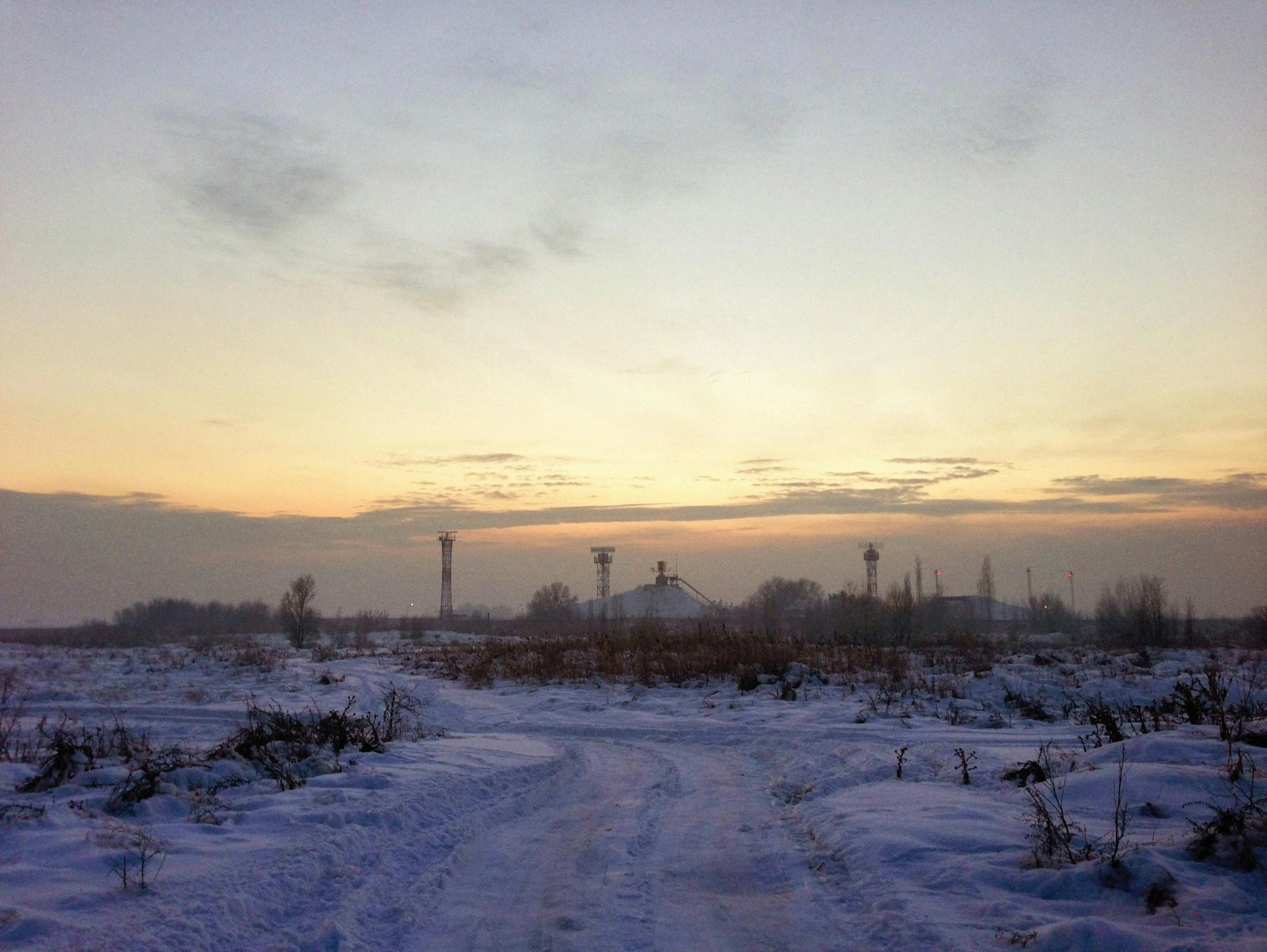 the snow covered pathway runs through a barren landscape