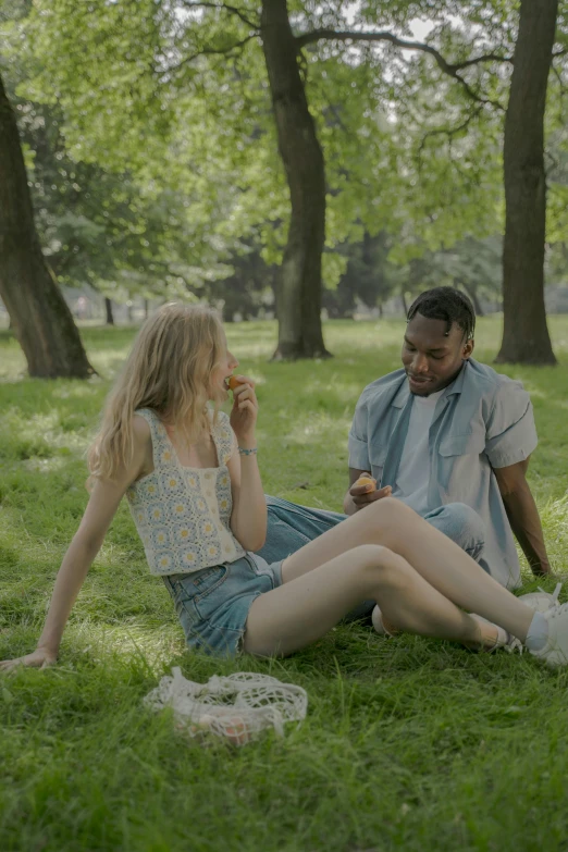 there are two people sitting on the grass talking to each other