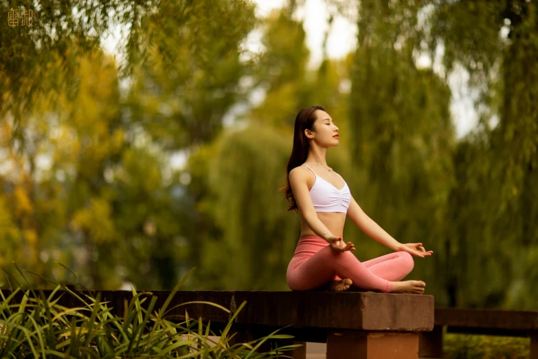 a woman doing yoga poses on a bench near the woods