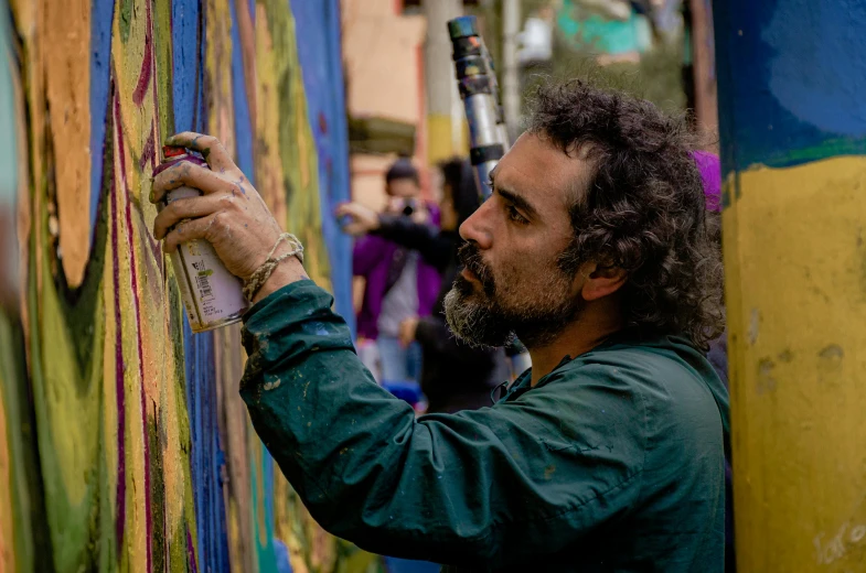 a man draws on a painting with chalk and paint
