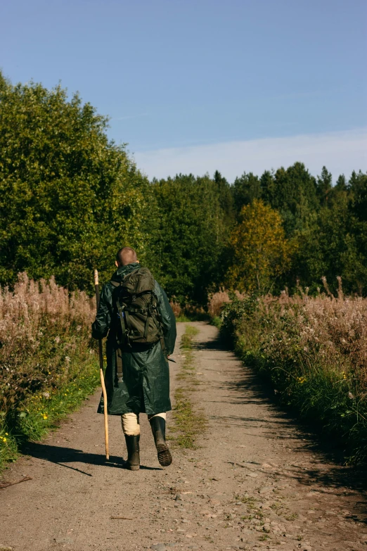 a man with a backpack and walking stick is walking in the road