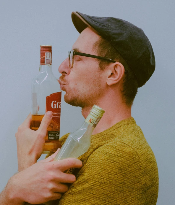 man holding bottle of liquor in front of him and nose to mouth