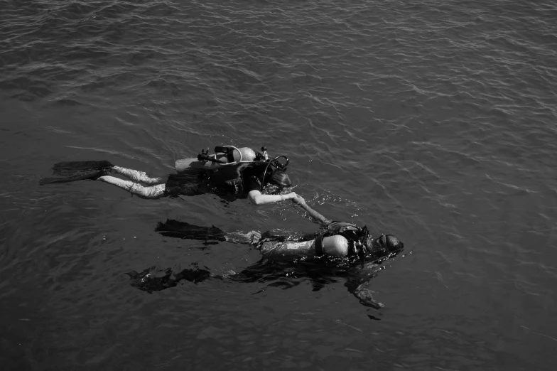 two people in scuba suits floating on top of a large body of water