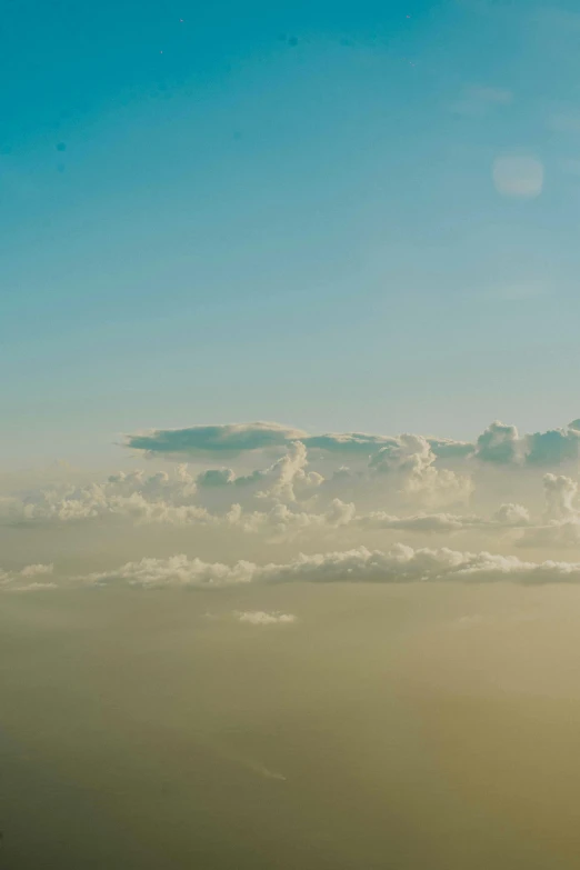 an airplane flying in the air, with large fluffy clouds overhead