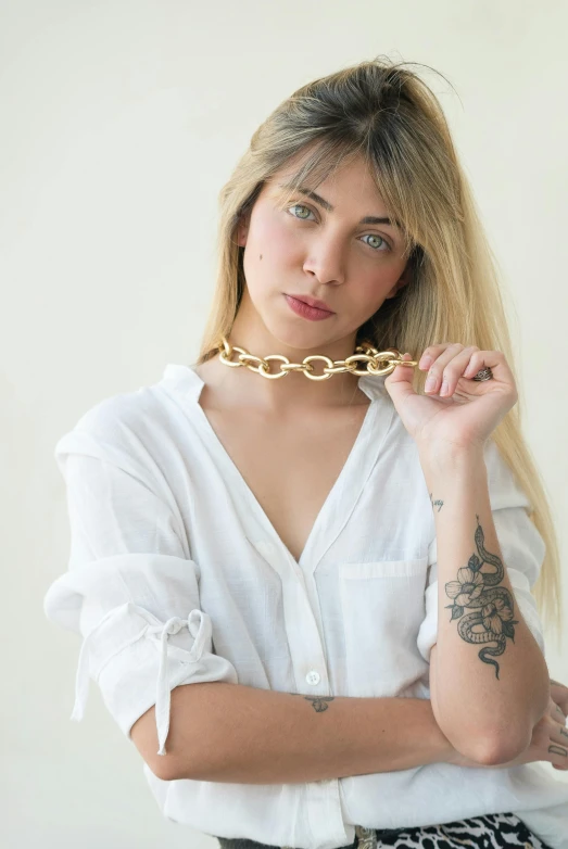 a woman wearing a white shirt and holding onto a gold chain