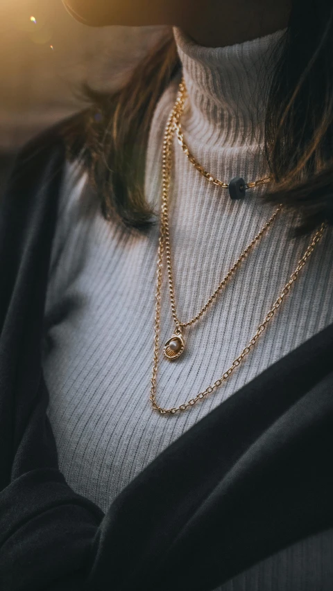 a girl is standing in the sun wearing a multi layer necklace