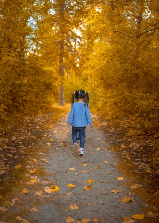 a girl walking through the woods carrying an umbrella