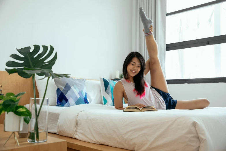 a woman laying on a bed reading a book