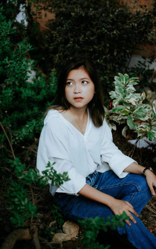 a woman in a white blouse sitting on the ground