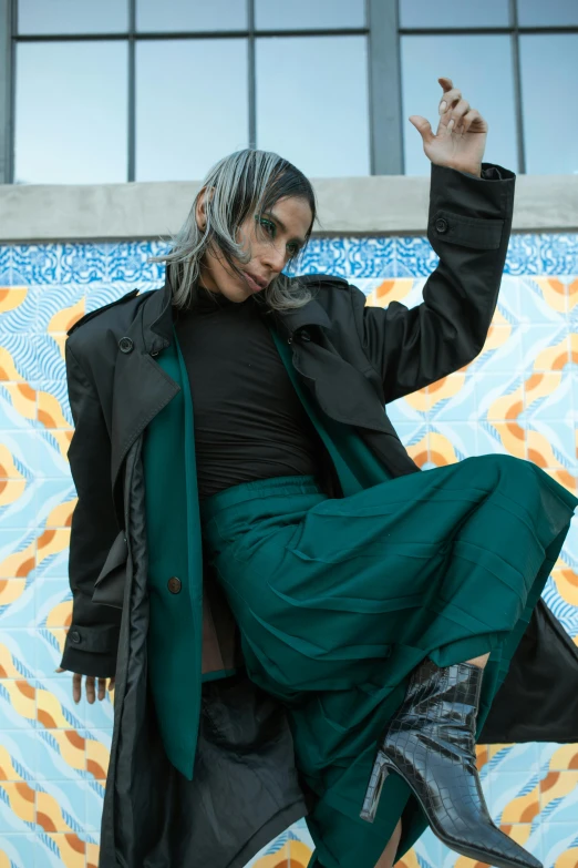 a woman in black top and green skirt in front of a mural