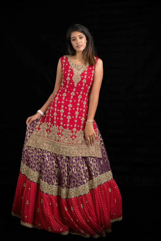 a woman is wearing a long red and yellow indian dress